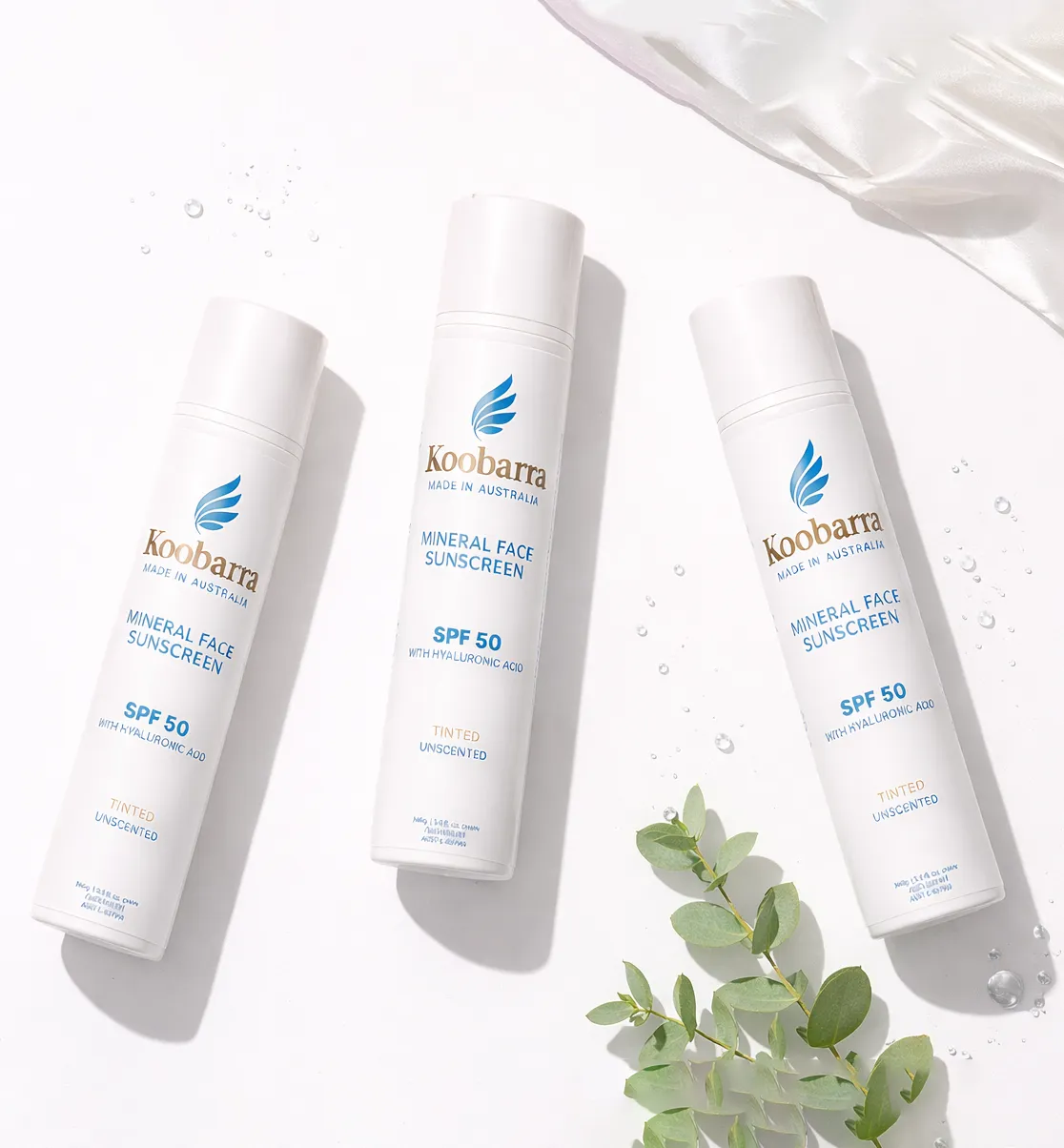 Three bottles of Koobarra Mineral Face Sunscreen on a white surface with eucalyptus